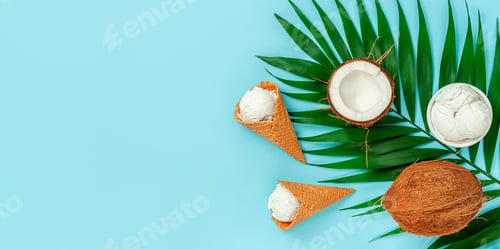 Preview: Coconut ice cream with palm leaf on vibrant blue background. Top view, copy space.