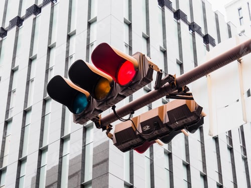 Preview: Low angle shot of hooded horizontal traffic lights hanging in a street
