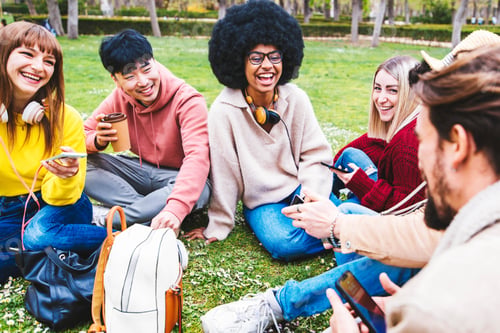 Preview: Group of multiracial students sitting in college campus