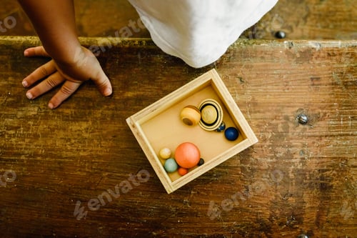 Preview: Child playing with small toy planets on an old wooden table.