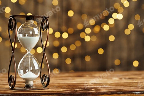 Preview: Hourglass on wooden desk against blurred lights