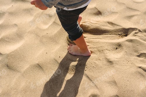 Preview: Feet of boy walking on the sand of the beach.
