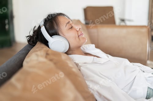 Preview: At home, listening to a playlist of music with headphones in the app, a woman audiobook is resting