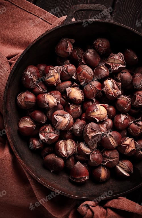 Preview: Roasted chestnuts, in an iron pan, wooden table, top view, no people, rustic style,