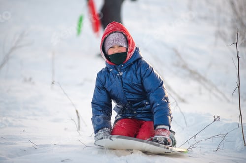 Preview: Happy child rides a sled down a snowy slope