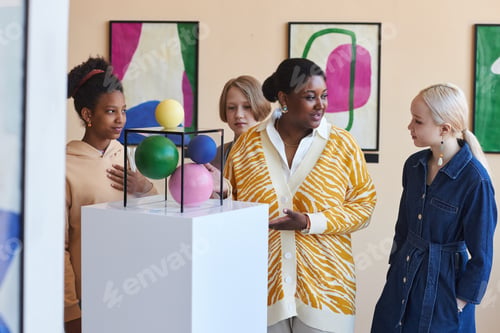Preview: Group of teenagers listening to tour guide in modern art gallery