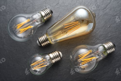 Preview: Transparent LED filament light bulbs on black slate background.