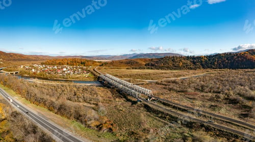 Preview: Long railroad bridge over river leading to valley settlement