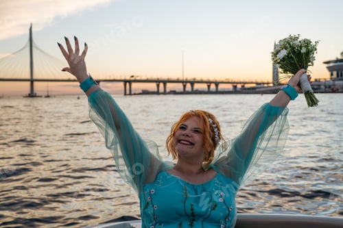 Preview: Portrait of cheerful redhead bride in blue dress in motorboat.