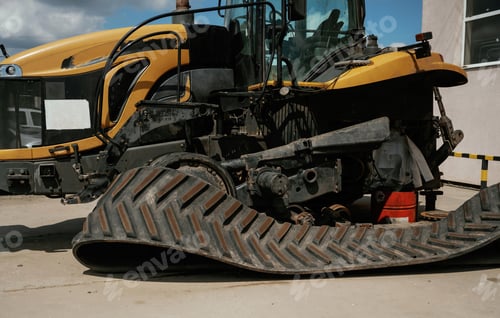 Preview: Industrial yellow bulldozer with damaged rubber track in repair yard