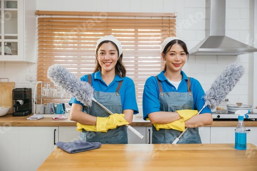 Preview: Two Asian young cleaning service women on kitchen counter with duster foggy spray and rag showcase