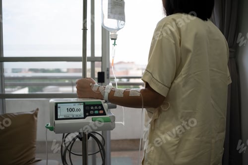 Preview: Middle-aged Asian female patient recovering from illness in hospital room, health care concept.