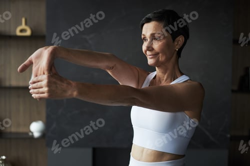 Preview: Middle Aged Caucasian Woman Stretching Hands during Home Fitness Routine