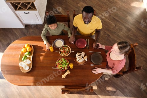 Preview: Contemporary young interracial family praying before eat