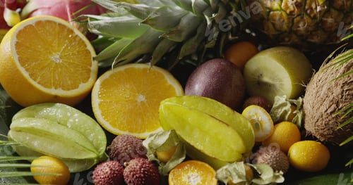 Preview: Assorted tropical fruits - halves of orange, pineapple, carambola, coconut and lichi with watering