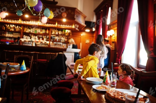 Preview: Children on birthdays sitting at the table and eating pizza.