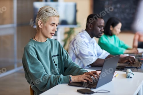 Preview: Side view of young classmates networking with focus on blond Asian guy