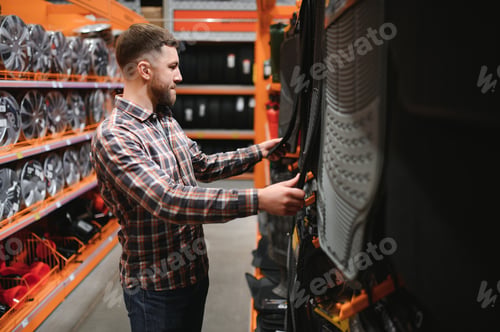 Preview: A man at the car shop or garage choosing floor carpets for his car from given examples