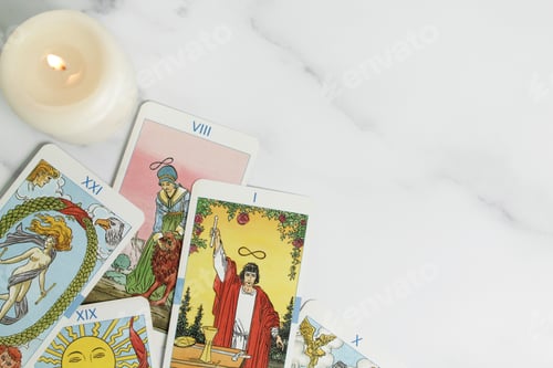 Preview: tarot cards and burning candle on marble background.