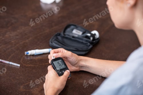 Preview: selective focus of woman holding glucose monitor at home