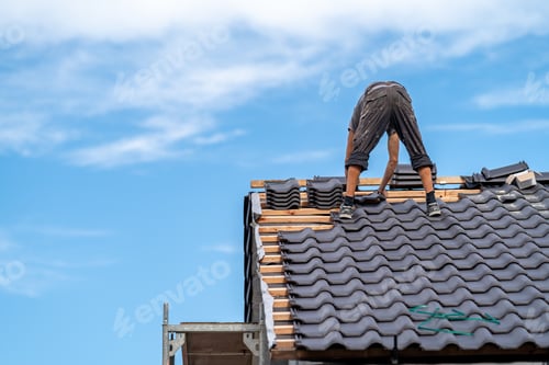 Preview: craftsman on the roof of a family house, building a roof covering from ceramic tiles, copy space