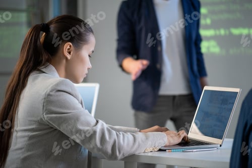 Preview: Young serious student sitting by desk and typing in front of laptop at lesson