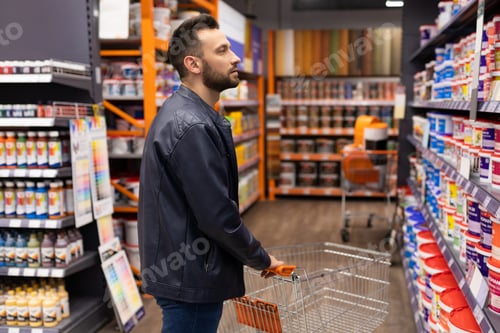 Preview: a buyer in a hardware store in front of a showcase with paints and enamels for decorating the walls