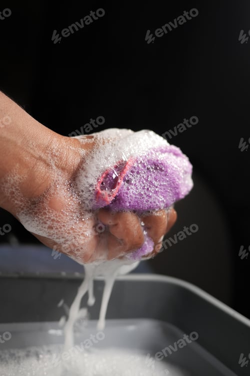 Preview: Washing a Colorful Sponge with Soap Suds in One Hand, Engaging in Cleaning