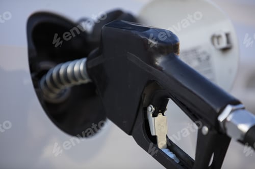 Preview: White car at a gas station being filled with fuel