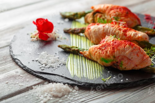 Preview: Asparagus rolled with chicken meat slices served on dark plate