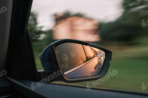 Preview: The sunset is reflected in the side mirror of the car in countryside