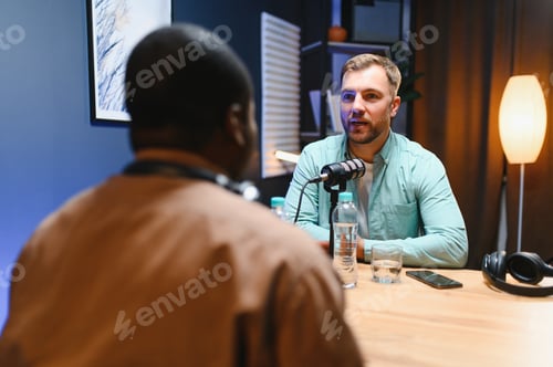 Preview: Man podcaster influencer blogger smiling while broadcasting his live audio podcast in studio