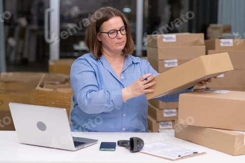 Preview: young entrepreneur SME laptop to manage operations packing orders boxes online sales. e-commerce