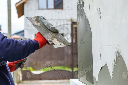 Preview: Construction worker covering house wall with adhesive cement glue