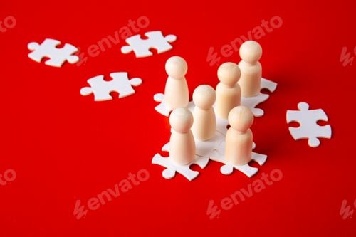 Preview: Wooden figures on puzzles on red background as a symbol of team building.