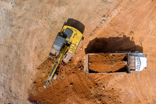 Preview: Excavator operator is carefully positioning the scoop on soil is into the dumper truck