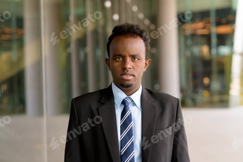 Preview: Portrait of African businessman wearing suit and tie outdoors in city