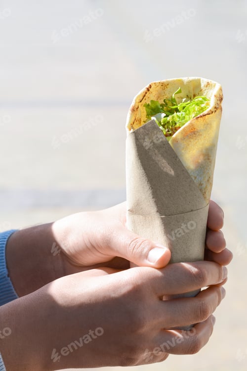 Preview: Woman holding delicious vegetable roll outdoors, closeup