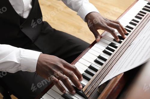 Preview: African-American man playing piano indoors, closeup. Talented musician