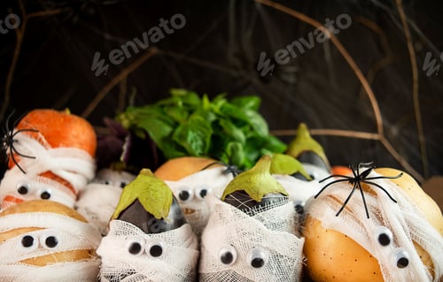 Preview: Halloween background. Creepy vegetables with eyes in medical bandages on a dark background