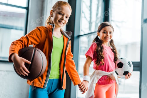 Preview: Cute kids with balls holding hands in gym
