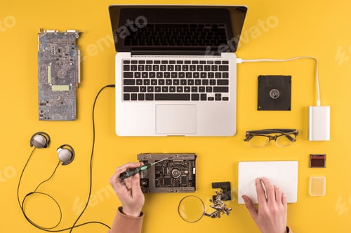 Preview: cropped shot of person fixing laptop on yellow