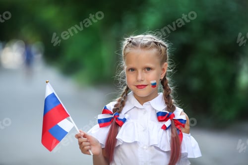 Preview: A school child stands on the outdoors and holds the flag of Russia.