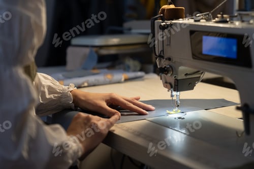 Preview: Closeup of female tailor work on sewing machine stitch fabric patterns for clothes. Garment industry