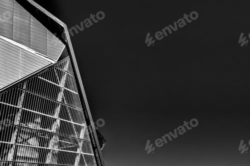 Preview: Closeup greyscale shot of a metal glass building under a clear sky
