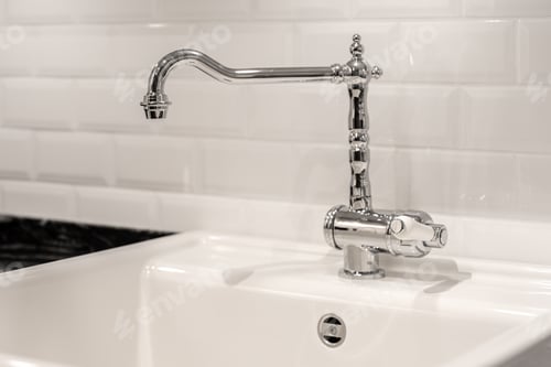 Preview: Modern kitchen faucet on white sink close up in minimal interior. Chrome tap with clean design.