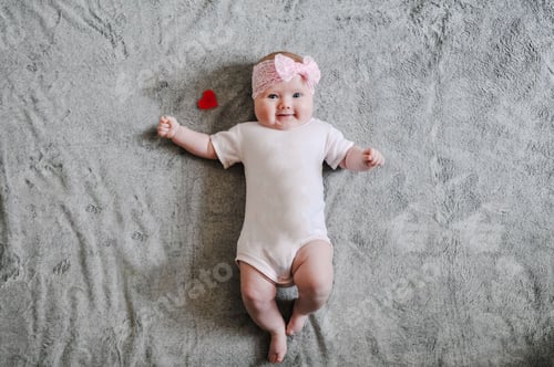 Preview: Little girl baby playing with toys, the baby lies on warm gray plaid, infant lying on the background
