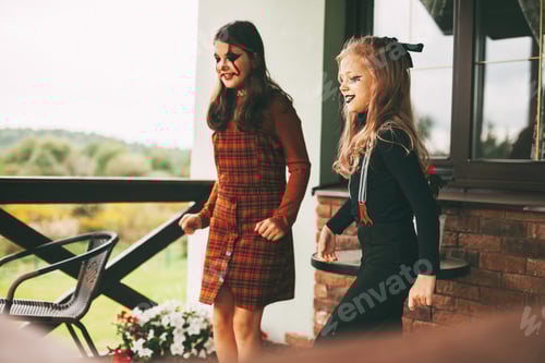 Visualização: Duas irmãs estão comemorando o Halloween na rua do lado de fora de sua casa, na natureza, fantasiadas