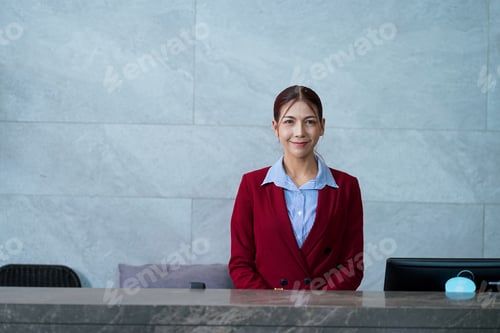 Preview: A woman in a red jacket stands at a reception desk