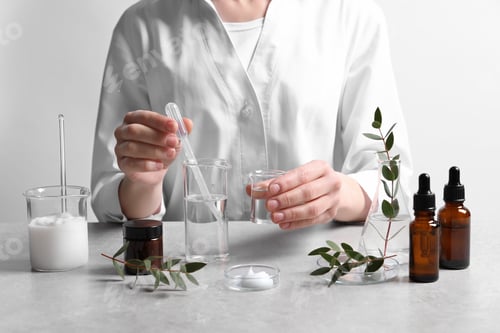 Preview: Scientist making cosmetic product at grey table in laboratory, closeup